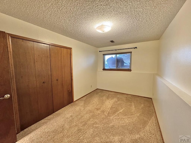 unfurnished bedroom with a textured ceiling, a closet, and light colored carpet