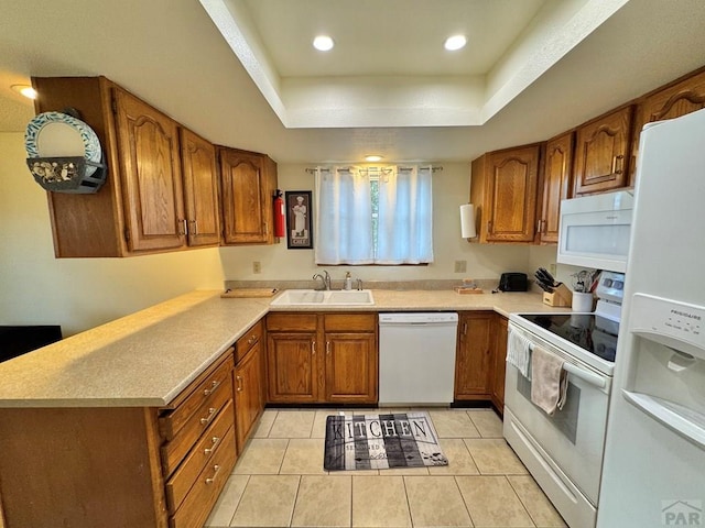 kitchen with white appliances, a sink, light countertops, brown cabinets, and a tray ceiling