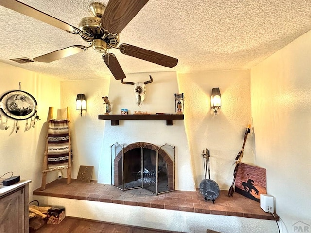 interior details with a textured ceiling, a fireplace, visible vents, and a ceiling fan