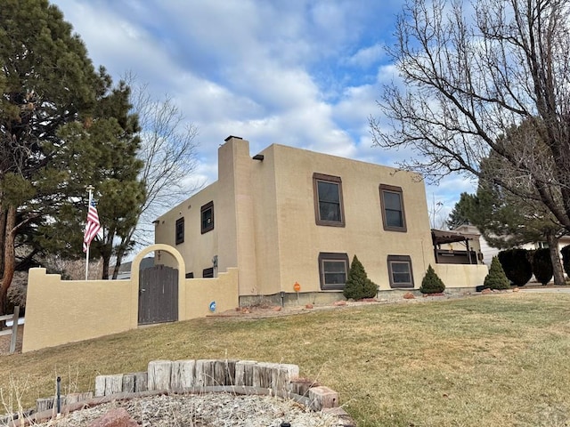 view of front facade with a chimney, stucco siding, a gate, fence, and a front lawn