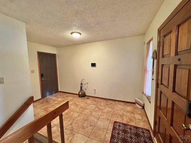 entryway featuring light tile patterned floors, baseboards, and a textured ceiling