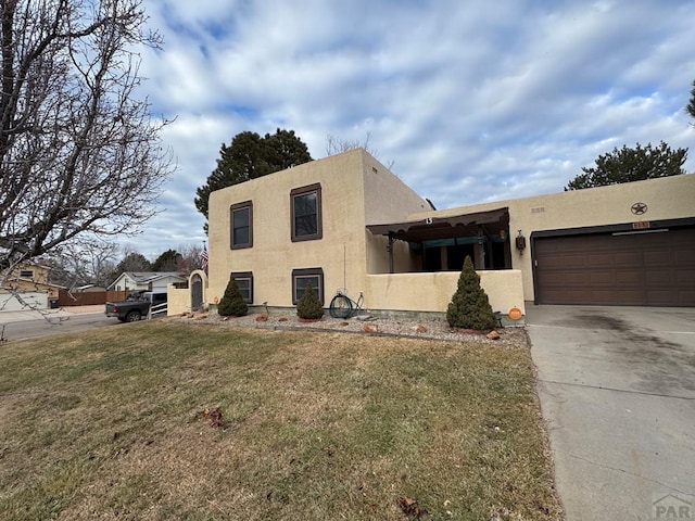 adobe home with a garage, a front yard, and stucco siding