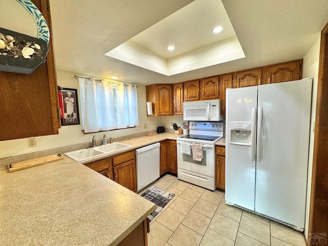 kitchen with brown cabinetry, white appliances, light countertops, and a sink