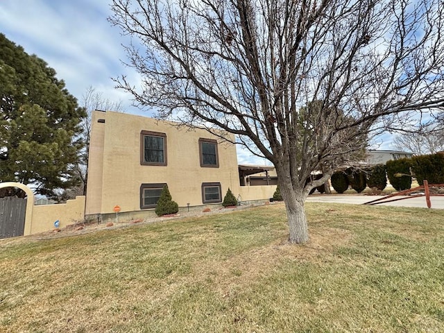 view of side of home featuring a yard, fence, and stucco siding