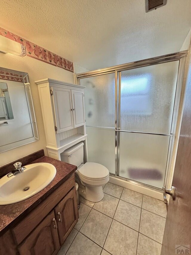 full bathroom featuring a stall shower, visible vents, tile patterned flooring, a textured ceiling, and vanity