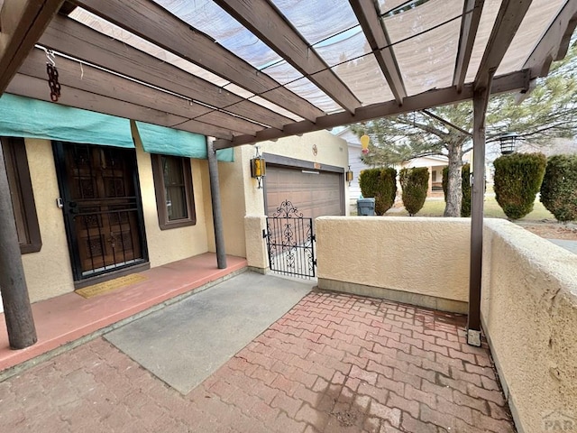 view of patio / terrace with a garage, a gate, fence, and a pergola