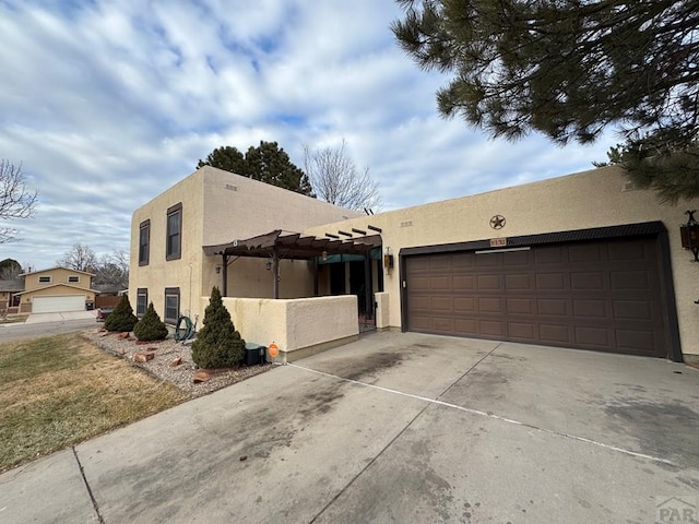 view of front of property with a garage, a pergola, driveway, and stucco siding