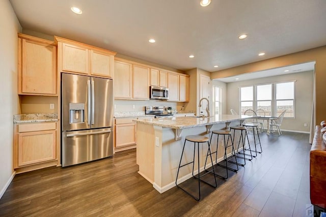 kitchen featuring dark wood finished floors, stainless steel appliances, a sink, and light brown cabinetry