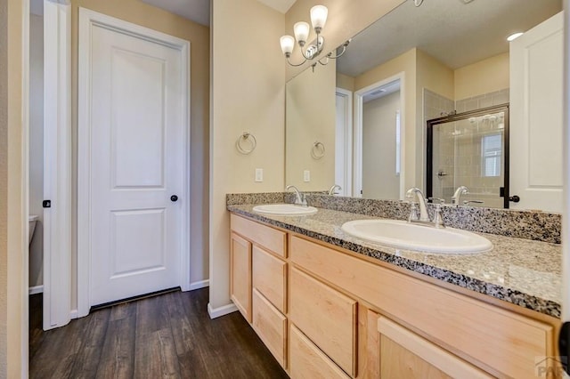 bathroom with double vanity, wood finished floors, a stall shower, and a sink