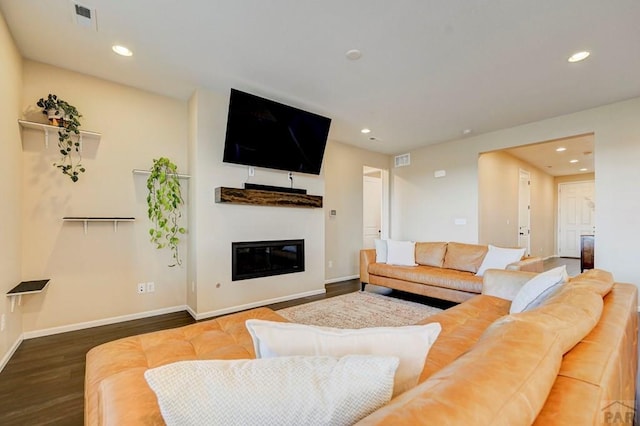 living area featuring baseboards, wood finished floors, a glass covered fireplace, and recessed lighting