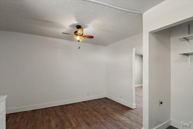 unfurnished room with a ceiling fan, a textured ceiling, baseboards, and dark wood-type flooring