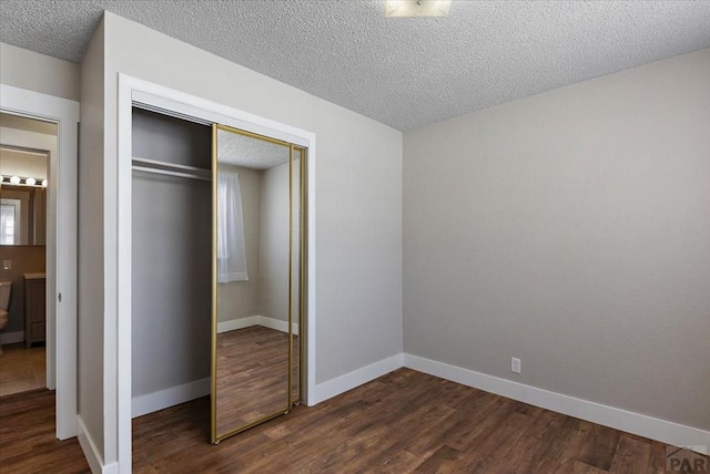 unfurnished bedroom featuring dark wood-style flooring, a closet, and baseboards