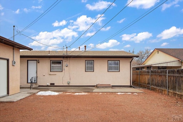 rear view of property featuring a shingled roof, a patio area, fence, and stucco siding