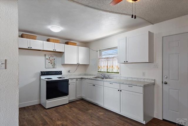 kitchen with dark wood-style floors, white range with electric stovetop, light countertops, white cabinets, and a sink