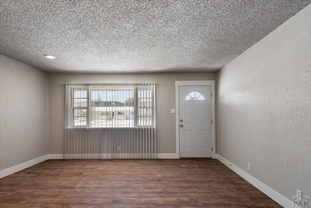 foyer entrance featuring baseboards, dark wood-type flooring, and a textured wall