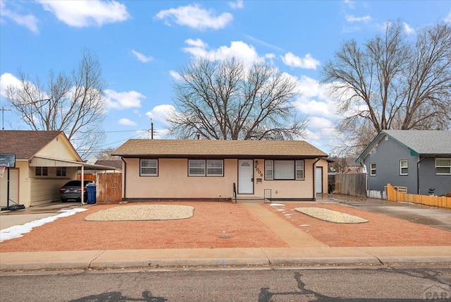 view of front facade featuring a carport, concrete driveway, fence, and stucco siding