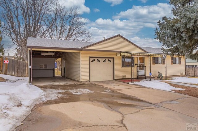 ranch-style house with a carport, fence, driveway, and an attached garage