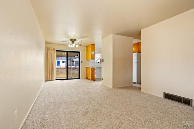 empty room featuring baseboards, a ceiling fan, visible vents, and light colored carpet