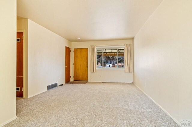 empty room featuring baseboards, visible vents, and light colored carpet