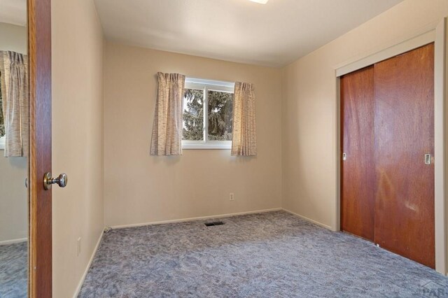 unfurnished bedroom with carpet, a closet, visible vents, and baseboards