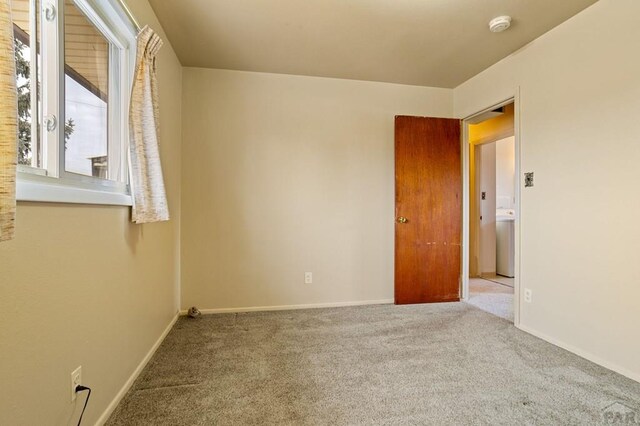 unfurnished room featuring light colored carpet and baseboards