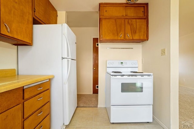 kitchen featuring brown cabinetry, white appliances, light countertops, and light carpet