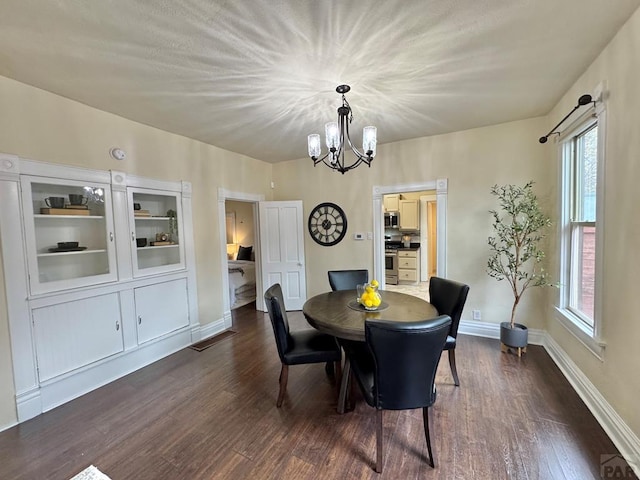 dining area featuring a notable chandelier, dark wood finished floors, and baseboards