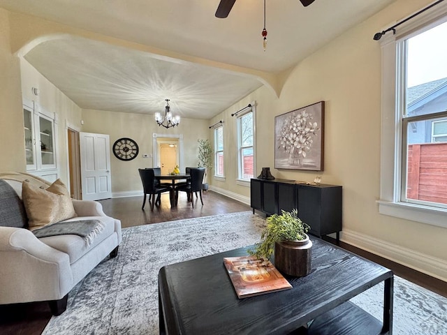 living room with baseboards, wood finished floors, and ceiling fan with notable chandelier