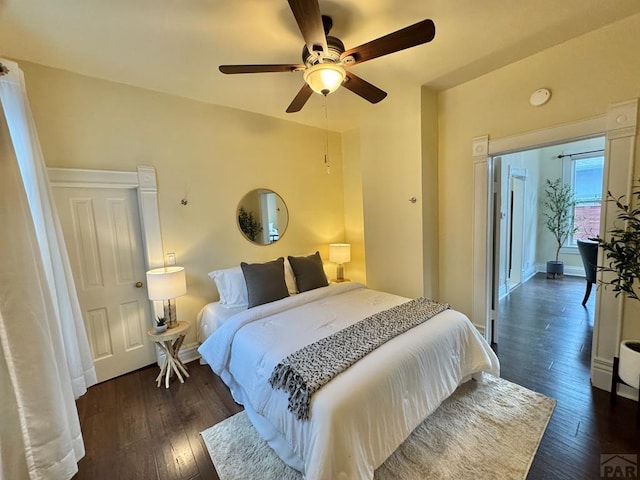 bedroom with dark wood-type flooring, a ceiling fan, and baseboards