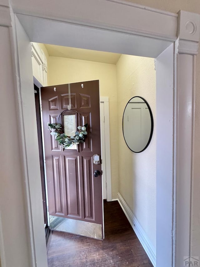 entrance foyer featuring dark wood-type flooring, vaulted ceiling, and baseboards