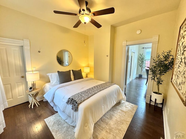 bedroom with ceiling fan, dark wood finished floors, and baseboards