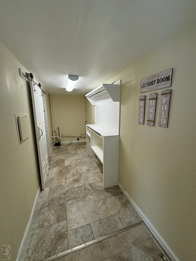 interior space with stone finish flooring, baseboards, and a barn door