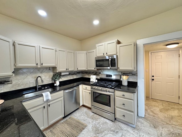 kitchen with appliances with stainless steel finishes, a sink, white cabinets, and decorative backsplash