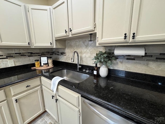 kitchen featuring dark stone counters, white cabinets, a sink, and backsplash