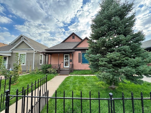 bungalow-style house featuring covered porch, a fenced front yard, a front lawn, and stucco siding