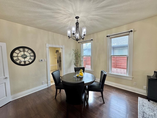 dining room with a chandelier, dark wood finished floors, a textured ceiling, and baseboards