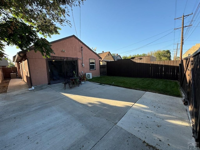 rear view of property featuring a patio, a lawn, a fenced backyard, and stucco siding