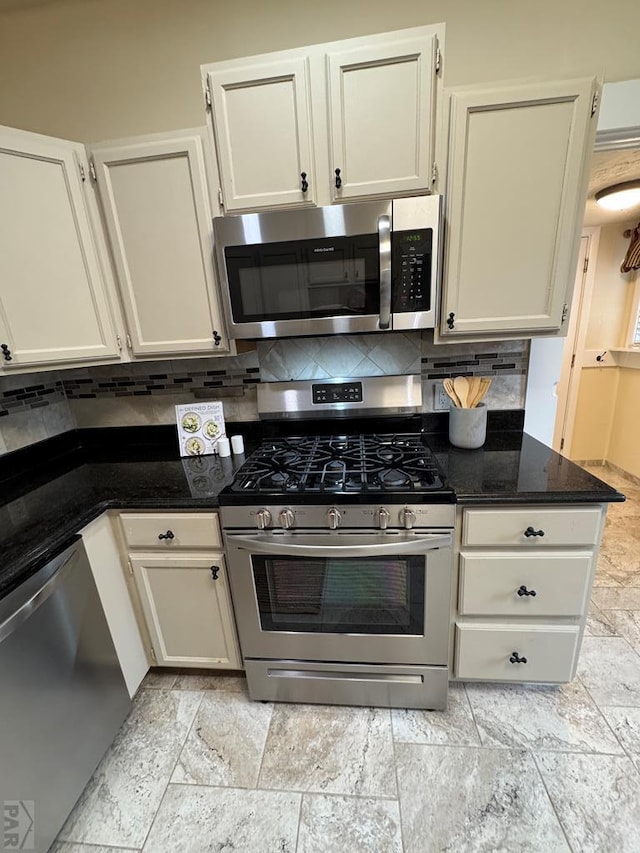 kitchen featuring dark stone counters, stainless steel appliances, white cabinetry, and decorative backsplash