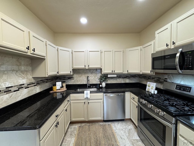 kitchen with white cabinets, decorative backsplash, stainless steel appliances, and a sink