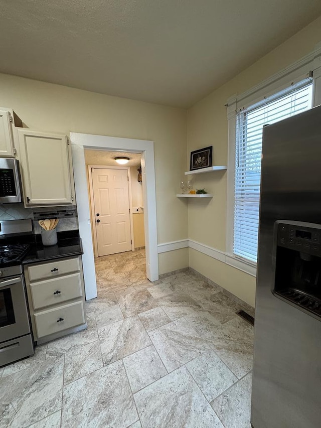 kitchen featuring baseboards, white cabinets, dark countertops, stainless steel appliances, and open shelves