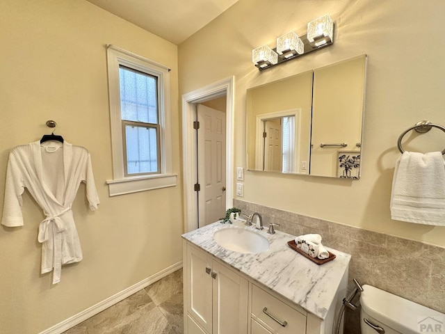 bathroom featuring baseboards, vanity, and toilet