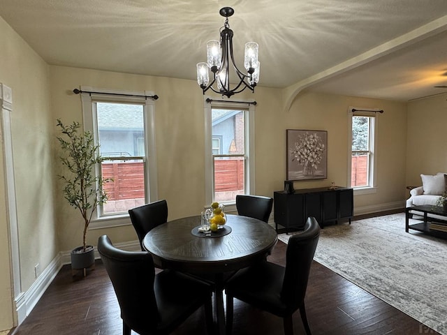 dining space featuring an inviting chandelier, dark wood finished floors, and baseboards