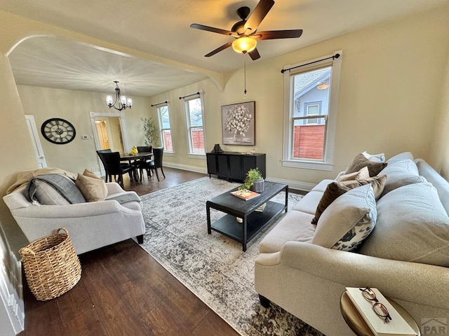 living area with baseboards, wood finished floors, and ceiling fan with notable chandelier