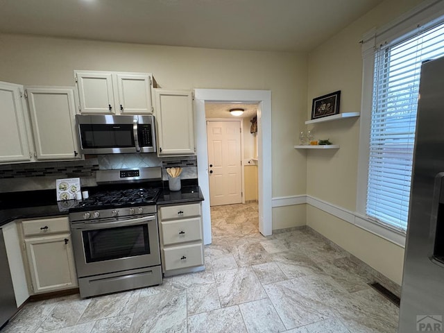 kitchen featuring stainless steel appliances, dark countertops, and white cabinetry