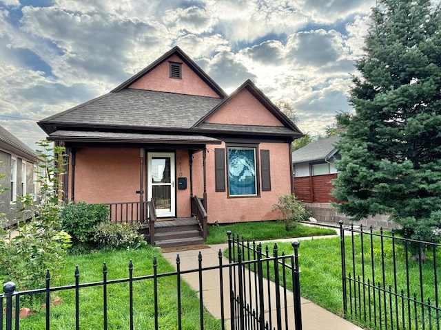 view of front of home with a shingled roof, a fenced front yard, a front yard, and stucco siding