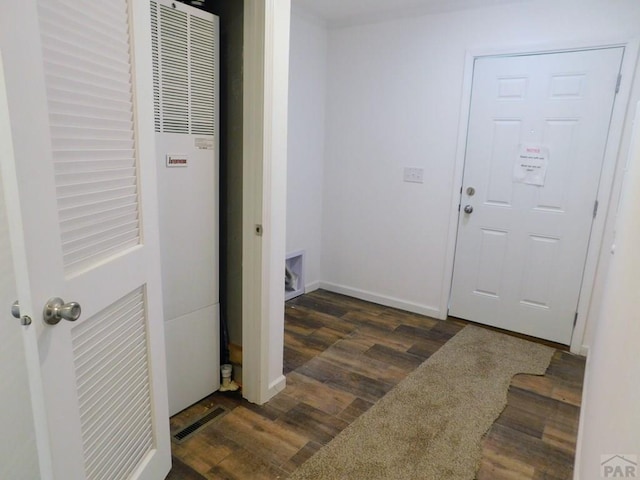 foyer entrance with dark wood-type flooring, a heating unit, visible vents, and baseboards