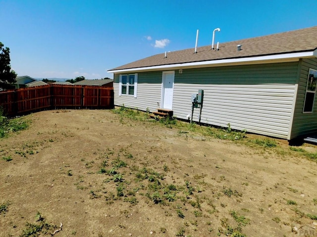 rear view of house featuring entry steps and fence