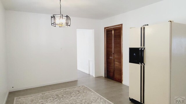 unfurnished dining area featuring baseboards and an inviting chandelier