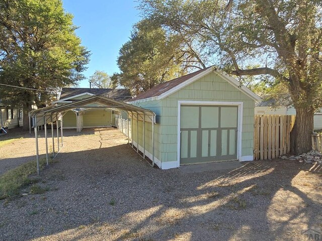 view of outdoor structure with fence, an outdoor structure, and a detached carport