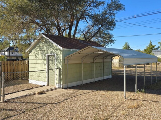 view of outdoor structure with an outdoor structure, fence, and a detached carport